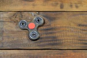 A rare handmade wooden fidget spinner lies on a brown wooden background surface. Trendy stress relieving toy photo