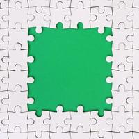 Framing in the form of a rectangle, made of a white jigsaw puzzle around the green space photo