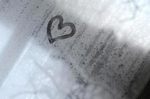 The heart is painted on the misted glass in the winter photo