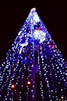 Blurred fragment of the New Year tree. Lots of round lights in blue photo