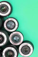 Several photographic lenses lie on a bright turquoise background. Copy space photo