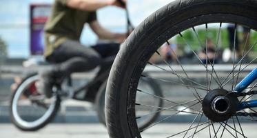 A BMX bike wheel against the backdrop of a blurred street with cycling riders. Extreme Sports Concept photo