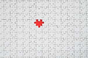 The texture of a white jigsaw puzzle in an assembled state with one missing element forming a red space photo