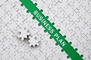 Business plan. The green path is laid on the platform of a white folded jigsaw puzzle. The missing elements of the puzzle are stacked nearby photo