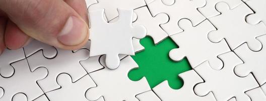 The human hand fills the last missing elements of the surface from the jigsaw puzzle. The concept of the completion of the initiated cases photo