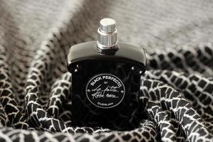 TERNOPIL, UKRAINE - SEPTEMBER 2, 2022 Black Perfecto La Petite Robe Noire by Guerlain perfume bottle on plaid in monochrome colors photo