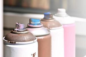 A few used aerosol paint sprayers lie on the windowsill in the workshop of a graffiti artist. The concept of street art and illegal drawing on the walls. Youth hobby photo