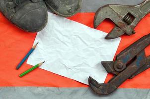 Adjustable wrenches with old boots and a sheet of paper with two pencils photo