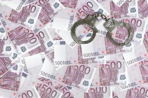 Handcuffs on five hundred euros background. Financial crime, dirty money and corruption concept - 500 money bills and dirty steel handcuffs photo