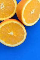 Top view of a several orange fruit slices on bright background in blue color. A saturated citrus texture image photo