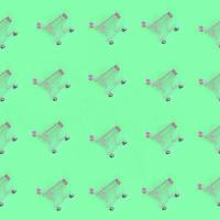 Shopping addiction, shopping lover or shopaholic concept. Many small empty shopping carts perform a pattern on a pastel colored paper background. Flat lay composition, top view photo