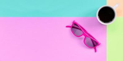 Small white coffee cup and pink sunglasses on background of fashion pastel pink, blue, coral and lime colors photo