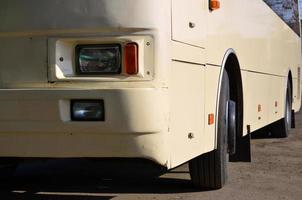 Photo of the hull of a large and long yellow bus. Close-up front view of a passenger vehicle for transportation and tourism