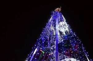 fragmento del árbol de año nuevo. muchas luces redondas de color azul están ubicadas en un marco cónico foto