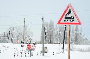 cruce ferroviario sin barrera con muchas señales de advertencia en la temporada de invierno con nieve foto