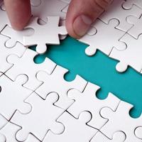 The human hand paves the way to the surface of the jigsaw puzzle, forming a blue space. The concept of overcoming the difficulties on the way to success photo