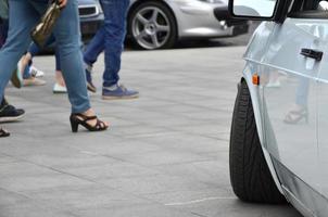 Diagonal view of a white glossy car that stands on a square of gray tiles photo