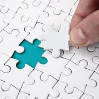 The human hand fills the last missing elements of the surface from the jigsaw puzzle. The concept of the completion of the initiated cases photo
