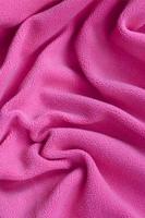 The blanket of furry pink fleece fabric. A background of light pink soft plush fleece material with a lot of relief folds photo
