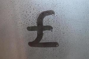 el símbolo de libras inglesas está escrito con un dedo en la superficie del vidrio empañado foto