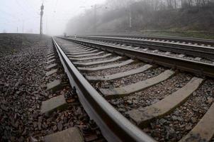 The railway track in a misty morning. A lot of rails and sleepers go into the misty horizon. Fisheye photo with increased distortion