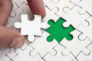 The human hand fills the last missing elements of the surface from the jigsaw puzzle. The concept of the completion of the initiated cases photo