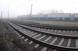 The Ukrainian suburban train rushes along the railway in a misty morning. Fisheye photo with increased distortion