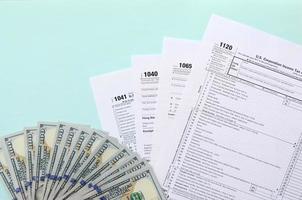 Tax forms lies near hundred dollar bills and blue pen on a light blue background. Income tax return photo