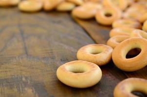 muchos bagels amarillos frescos yacen en la superficie de la vieja madera oscura. un tipo popular de productos de harina. uno de los dulces tradicionales rusos para el té foto