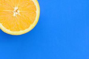 vista superior de una rodaja de fruta naranja sobre fondo brillante en color azul. una imagen de textura cítrica saturada foto