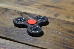 A rare handmade wooden fidget spinner lies on a brown wooden background surface. Trendy stress relieving toy photo