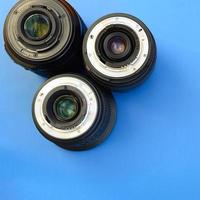 Several photographic lenses lie on a bright blue background. Space for text photo