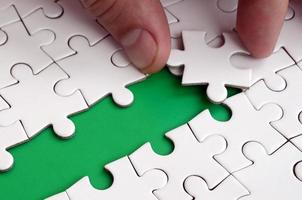 The human hand paves the way to the surface of the jigsaw puzzle, forming a green space. The concept of overcoming the difficulties on the way to success photo