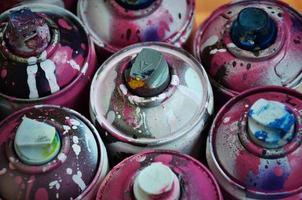 Still life with a large number of used colorful spray cans of aerosol paint lying on the treated wooden surface in the artist's graffiti workshop. Dirty and stained cans for spray art photo