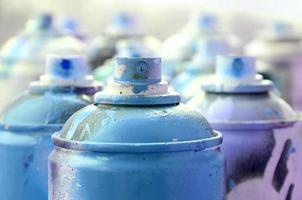 A lot of dirty and used aerosol cans of bright blue paint. Macro photograph with shallow depth of field. Selective focus on the spray nozzle photo