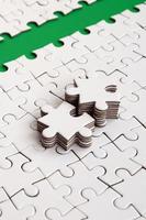 The green path is laid on the platform of a white folded jigsaw puzzle. The missing elements of the puzzle are stacked nearby. Texture image with space for text photo