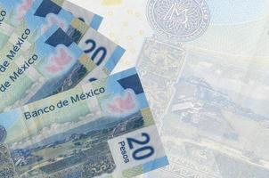 Los billetes de 20 pesos mexicanos se encuentran apilados sobre el fondo de un gran billete semitransparente. fondo de negocios abstracto foto