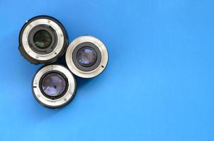 Several photographic lenses lie on a bright blue background. Space for text photo