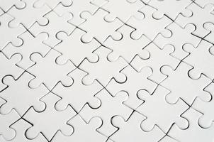 Close up of a white jigsaw puzzle in assembled state in perspective. Many components of a large whole mosaic are united photo
