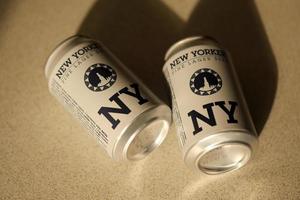 TERNOPIL, UKRAINE - JULY 18, 2022 Two cans of New Yorker fine lager beer with original logo and design on brown retro background photo