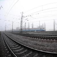 The Ukrainian suburban train rushes along the railway in a misty morning. Fisheye photo with increased distortion