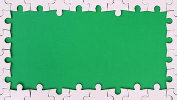 Framing in the form of a rectangle, made of a white jigsaw puzzle around the green space photo