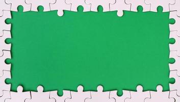 Framing in the form of a rectangle, made of a white jigsaw puzzle around the green space photo