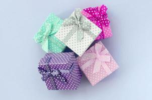 Pile of a small colored gift boxes with ribbons lies on a violet background photo