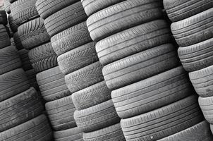 Old used tires stacked with high piles in secondary car parts shop garage photo