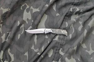 cuchillo militar en ropa de camuflaje del ejército de cerca. fondo con espacio de copia para el diseño de servicios militares o especiales foto
