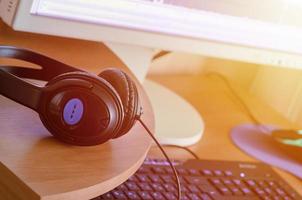 Big black headphones lie on the wooden desktop of the sound designer photo