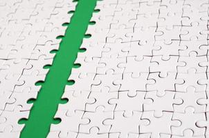 The green path is laid on the platform of a white folded jigsaw puzzle. Texture image with copy space for text photo