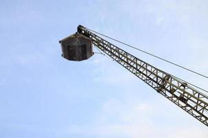 Old yellow mechanical clamshell grab on blue sky background photo