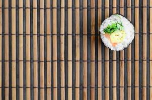 Sushi roll lie on a bamboo straw serwing mat. Traditional Asian food. Top view. Flat lay minimalism shot with copy space photo